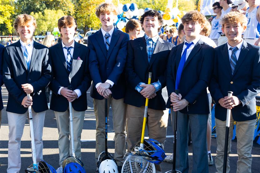 High school boys wearing suits stand during the homecoming parade